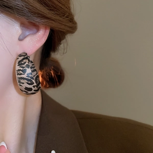 Macro detail of large animal print hoop earring worn with professional brown blazer