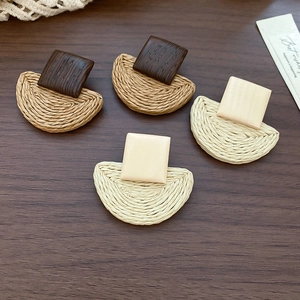 Detail of square wood and raffia geometric earrings in natural brown and beige shades