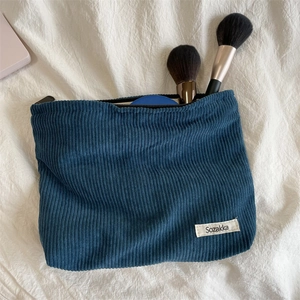 Detail of navy corduroy makeup bag showing texture, zipper, and storage capacity