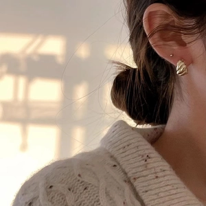 Close-up of golden wavy hoop earrings on model with warm vintage French aesthetic
