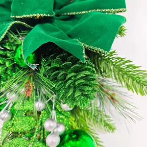 Détail d'un nœud en velours vert avec pommes de pin et boules pour guirlande de Noël