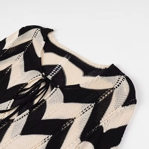 Detail des V-Ausschnitts mit Bindeband und schwarz-weißem Chevron-Strickmuster