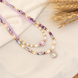 Dettaglio di una collana a strati con pietre naturali e ciondolo a forma di occhio