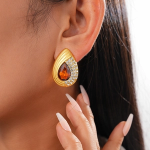 Detailed close-up of vintage golden teardrop earrings with amber stones and micro-pave diamonds