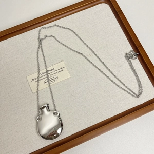 Detailed view of silver perfume bottle pendant necklace on a natural wooden tray