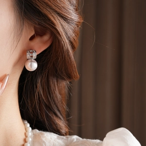 Detailed view of luxury gold-plated pearl earrings with sparkling diamond accents