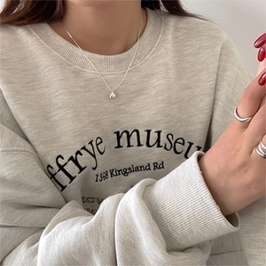 Detail of silver water-drop necklace and rings worn with casual sweatshirt for daily style