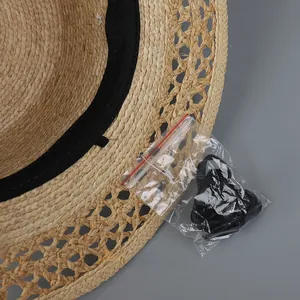 Detail of hollow woven straw hat featuring black inner sweatband and windproof rope accessory