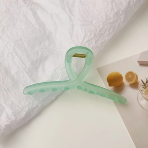 Détail d'une pince à cheveux vert menthe dépolie avec ressort sur fond esthétique blanc