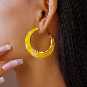 Close-up of yellow marble textured C-shape hoop earring on model with gold clasp