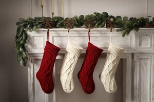 Close-up of four cable knit Christmas stockings in red and cream on a rustic fireplace