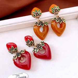Detail of vintage strawberry earrings with enamel finish and carved leaf hooks