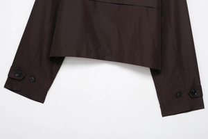 Detailed close-up of dark brown trench coat featuring adjustable double-button cuffs