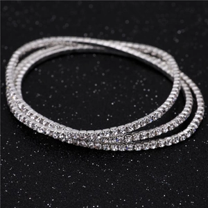 Close-up of triple-layer silver elastic rhinestone bracelets sparkling on a dark background