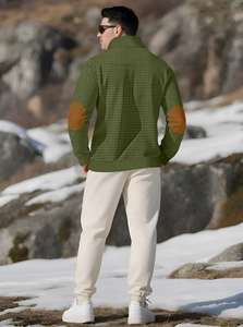 Detail of army green quilted pullover with brown elbow patches on outdoor model