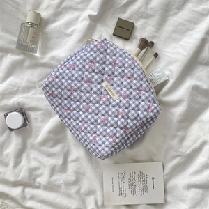 Detail showing spacious interior of quilted checkered bow pouch with makeup brushes