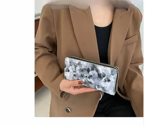 Detail of long marble texture wallet with golden zipper held by a fashion model