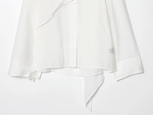 Detailed close-up of white semi-transparent cotton linen blouse hem and sleeve texture