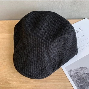 Detailed texture of black knit fabric on vintage newsboy cap over wooden surface