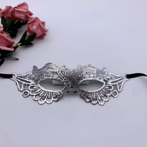 Detailed close-up of silver lace masquerade mask with floral embroidery and satin ties