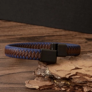 Detail of woven brown and blue leather bracelet with black magnetic metal clasp on stone