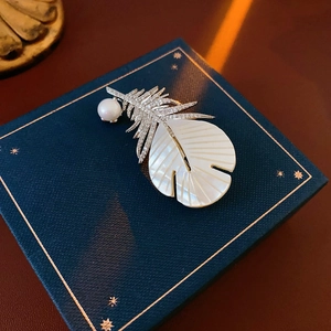 Detailed view of feather brooch with shimmering zircon and pearl on jewelry box