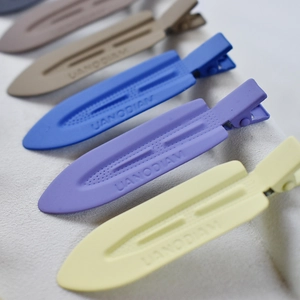 Close-up of matte acetate hair clips in gradient colors with embossed UANODIAM lettering