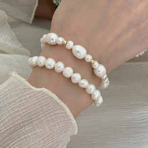 Macro shot of layered natural freshwater pearl bracelets with gold-plated beads on wrist
