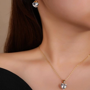 Gold heart jewelry set with necklace and earrings featuring clear zircon stones on model