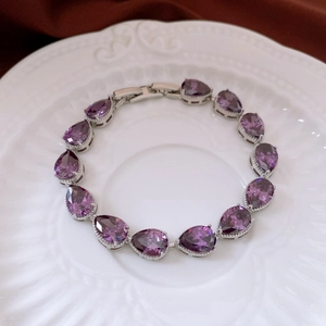 Detailed view of pear-cut purple zircon gemstones set in a silver-tone link bracelet