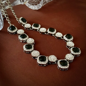 Close-up of geometric square black crystals and pavé diamonds on a silver necklace