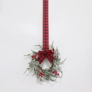 Detailed view of snowy Christmas wreath with red berries and a red plaid ribbon bow