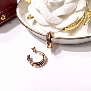 Detail of rose gold triple-intertwined circle earrings on white ceramic decor