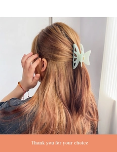 Detail of a mint green butterfly hair claw clip with pearl accents on long wavy hair