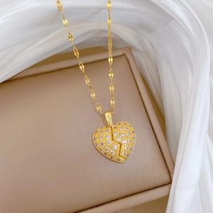 Close-up of golden titanium steel necklace with a glittering heart pendant and broken heart detail