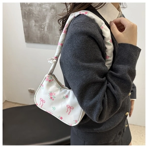 Detail of white underarm bag featuring pink floral prints and ribbon bow patterns