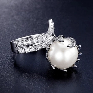 Macro shot of elegant faux pearl ring with shimmering diamond-encrusted silver band