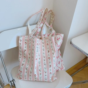Pink floral canvas tote bag set with stripe patterns and ribbon detail on a chair