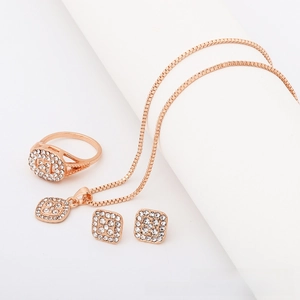 Close-up of rose gold jewelry set with geometric square pendants and sparkling crystals