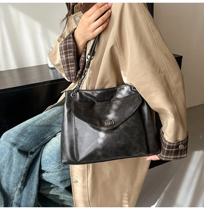 Dettaglio della trama in pelle vintage marrone scuro e della tracolla a catena