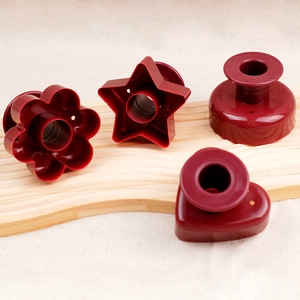 Red plastic donut and cookie cutters set with handles on a wooden board for baking