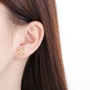 Vue macro de boucles d'oreilles fleur à quatre feuilles dorées et pavé de zircones