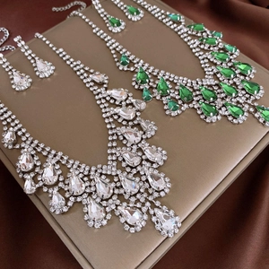 Detailed view of teardrop crystal necklaces in white and green on silk fabric