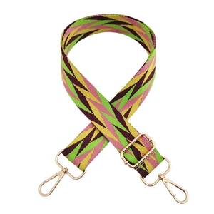 Detail of adjustable wide woven bag strap with colorful geometric zigzag patterns and gold buckles