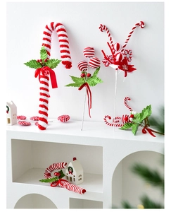Detail of red and white striped Christmas candy cane ornaments with festive berries
