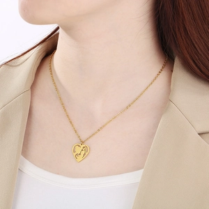 Detail of a gold heart pendant with a mother-child embrace silhouette on model's neck
