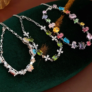 Detailed shot of multi-colored zircon stones on silver bracelets against green velvet