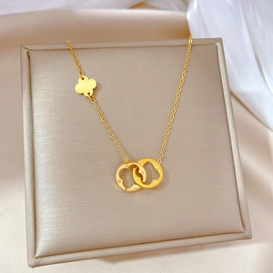 Minimalist gold titanium steel necklace with interlocking rings and clover pendant on silk