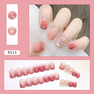 Macro view of peach-themed pink gradient press-on nails with gold glitter and 3D accents