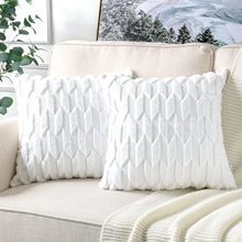 Detail of white plush pillow cover with textured geometric relief on a beige sofa